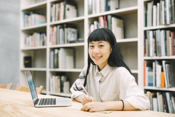 istock Smiling female student studying at desk in library 1172201303
