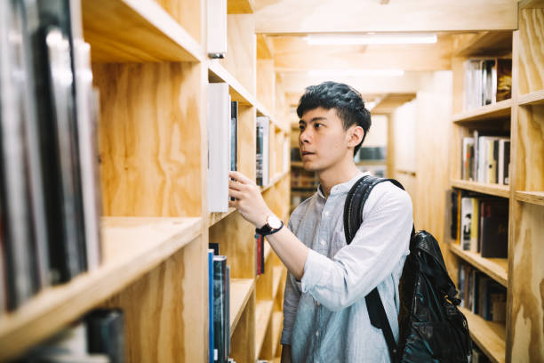 istock University student looking at bookshelf in library 1172201309