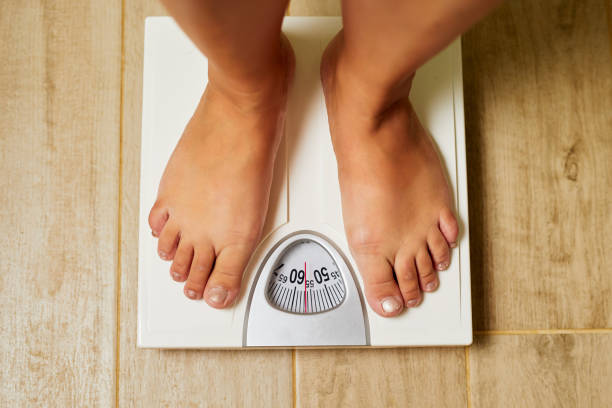 istock Female bare feet on weight scale in a bathroom 1172202188