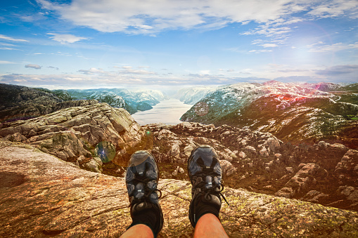 Feet and a landscape view over Lysefjorden, Norway, in summer with blue sky