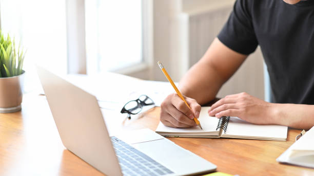 istock Close-up man's hands writing on notebook paper and laptop. 1172206506