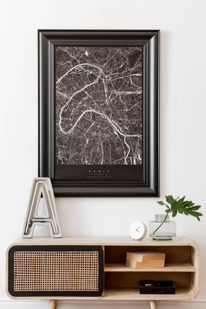 istock Modern scandinavian living room interior with black mock up poster map frame, design commode, big cement letter, tropical leaf, books and elegant accessories. Template. Stylish home decor. White wall 1172206892