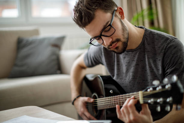 istock Young man playing guitar at home 1172207444