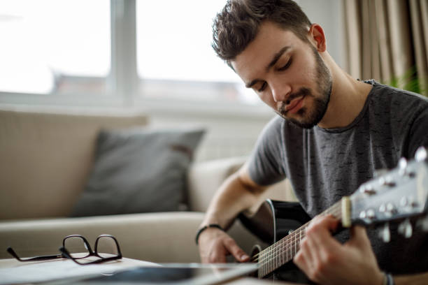 istock Young man playing guitar at home 1172207976