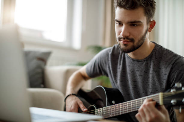 istock Young man playing a guitar at home 1172207986