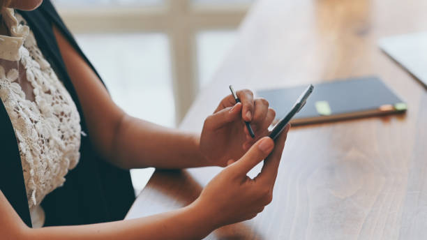 istock Closeup female using smartphone with pen on table. 1172207999