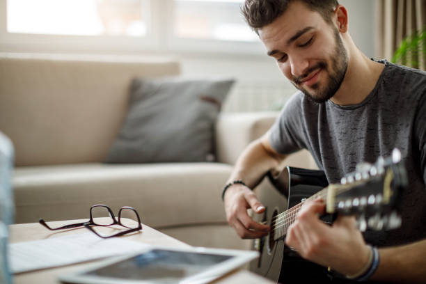 istock Young man playing a guitar at home 1172208030