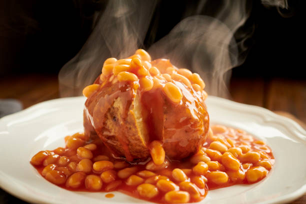 Baked Potato sliced open filled with steaming hot baked beans served on a white plate. Baked Potato sliced open filled with steaming hot baked beans served on a white plate. baked beans stock pictures, royalty-free photos & images