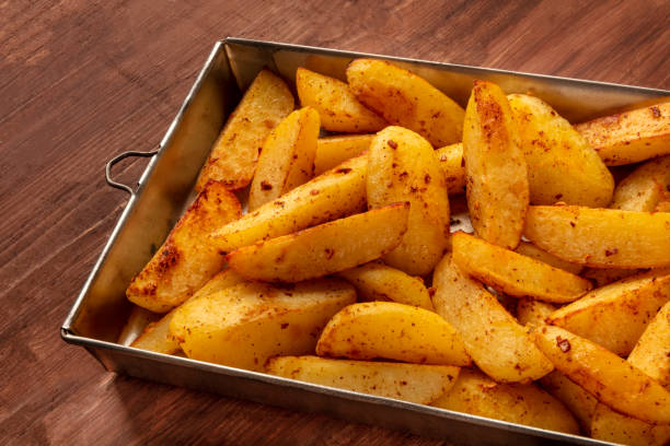 kliny ziemniaczane, pieczone w piecu, w zabytkowej blasze na ciemnym, rustykalnym drewnianym tle - prepared potato oven roasted potatoes roasted zdjęcia i obrazy z banku zdjęć