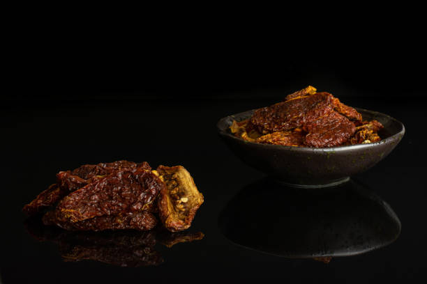 istock Red dried tomato isolated on black glass 1172214980