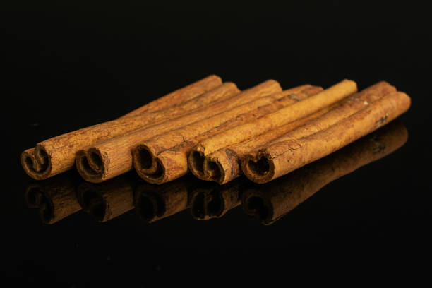 Group of five whole dry brown cinnamon isolated on black glass