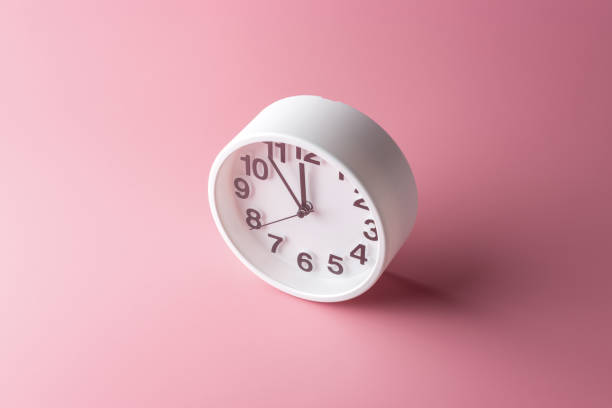 istock White clock on bright pink background. Minimal time concept. 1172216292
