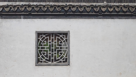 Traditional chinese window on white wall with black roof tiles