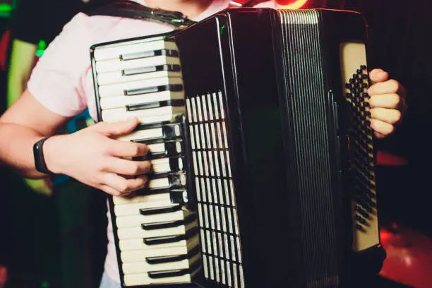 Close-up musician playing the accordion against a black background