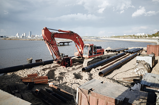 Digging excavator on river coast and making a pier. Kazan city, Russia