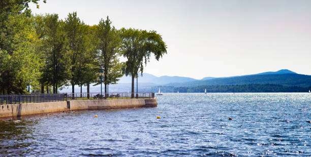 Panoramic view of Lake Memphremagog's coastline from Magog in Quebec's Eastern townships Panoramic view of Lake Memphremagog's coastline in Quebec's Eastern townships on a sunny Summer day. to the left is the Pointe Merry park. lake magog photos stock pictures, royalty-free photos & images