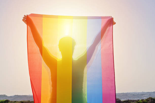 lgbt 무지개 깃발을 흔들며 손을 들고 있는 젊은 여성 - pride month 뉴스 사진 이미지