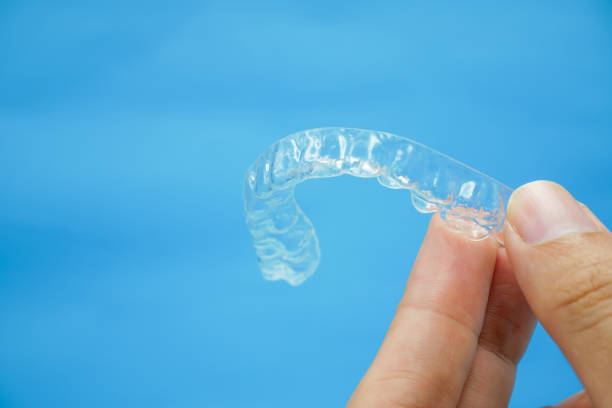 istock hand holding clear plastic retainer teeth that isolated on blue sky background 1172225960