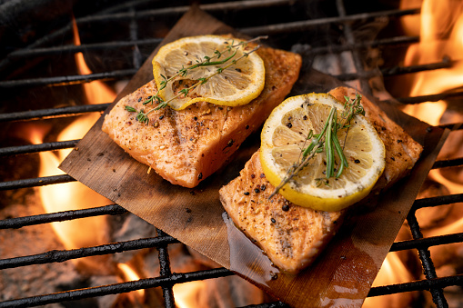 Beautiful sockeye salmon filet on a fiery grill with lemon slices and butter, part of a ketogenic or low carb diet.