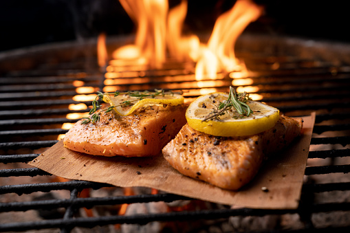 Beautiful sockeye salmon filet on a fiery grill with lemon slices and butter, part of a ketogenic or low carb diet.