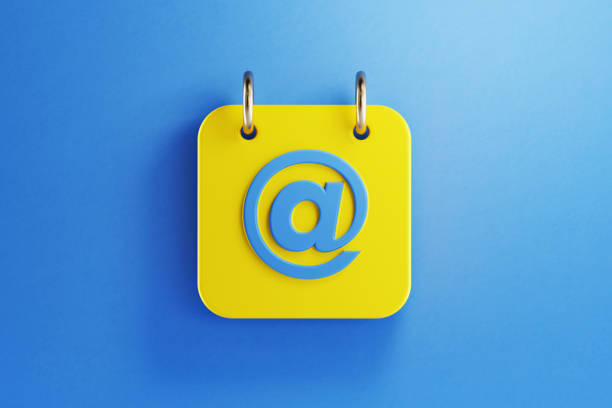 Yellow calendar with blue at symbol on blue background. Horizontal composition with copy space. Top view.
