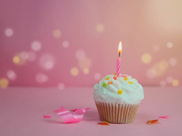 istock Happy birthday cupcake and bow candle on pink background with copy space. 1172238071