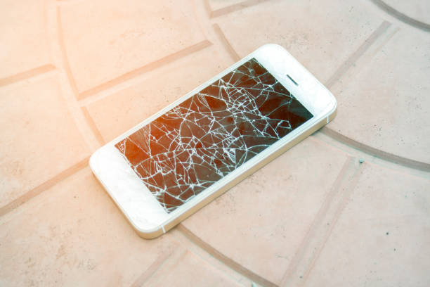 istock broken smartphone screen. Smartphone with a broken screen on the tile floor. Side view broken phone. negligence 1172243474