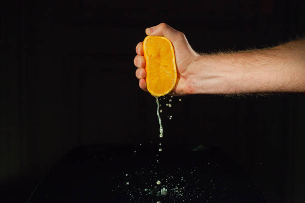 남자 짜기 반 의 수분이 많은 오렌지 에 검정 배경 - 짜냄 뉴스 사진 이미지