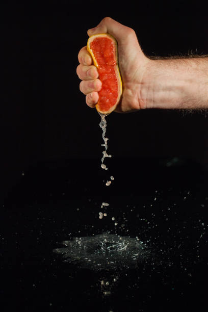 istock Grapefruit juice splashes from half of fruit held in man's hand 1172244364