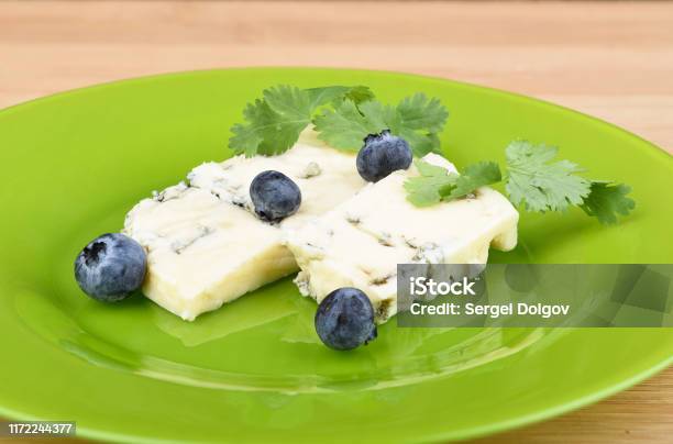 Blueberries And Cilantro Leaves On Slices Of Delicious Blue Mold Cheese On A Green Plate Stock Photo - Download Image Now