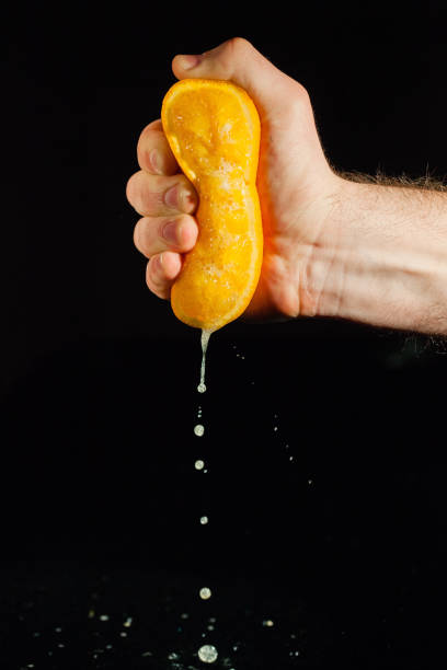 istock Drops of juice fall from an orange in man's hand 1172244576