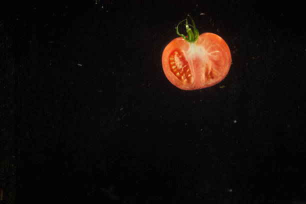 istock Half of red tomato falls in black aquarium 1172247249