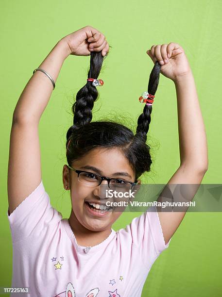 Один Веселый Индийская Девочка Держит Ее Plaits На Зеленом Фоне — стоковые фотографии и другие картинки 10-11 лет