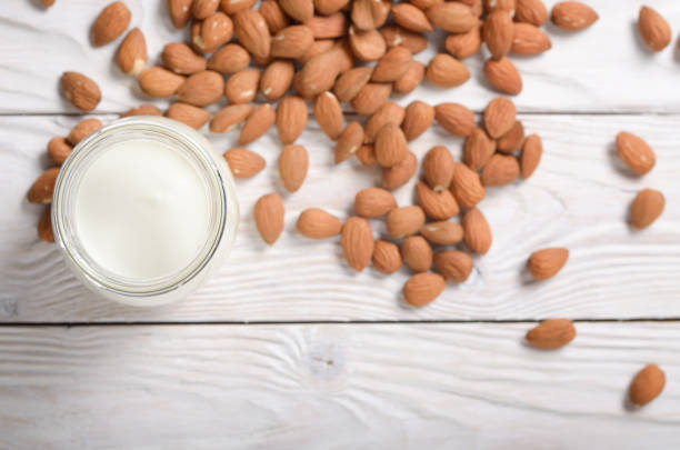 istock Milk or yogurt in mason jar on white wooden table with almonds aside flat lay view 1172256470