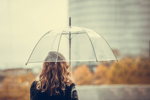 町に透明な傘を持つ孤独な女性。秋 - umbrella women storm yellow ストックフォトと画像