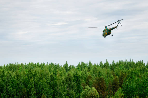 вертолет цвета хаки летит в небе над лесом - rescue helicopter outdoors occupation стоковые фото и изображения