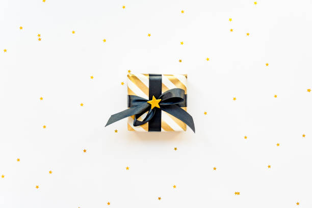 istock Gift box over star shaped golden sequins on a black background. 1172259950