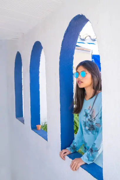 Asian tourist with in Mediterranean arch white arcade and blue sunglasses