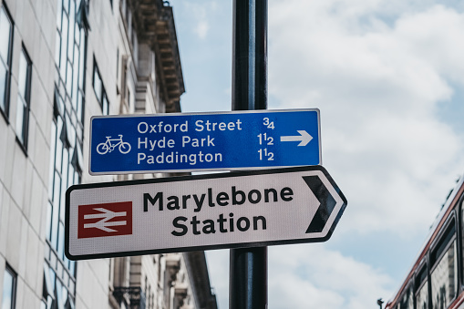 London, UK - July 18, 2019: Directional signs to Marylebone Station and cycling routes with distances to tourist attracting in London. Cycling is a popular way to get around the city.