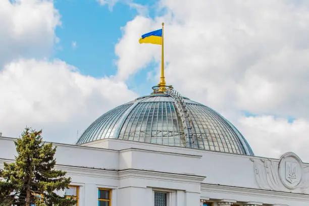Ukrainian flag on the dome of the parliament building. Yellow-blue flag on a background of the sky with clouds.