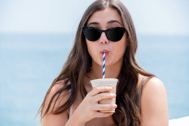 young woman in sunglasses drinking iced coffee at the beach - horizon over water malibu california usa imagens e fotografias de stock