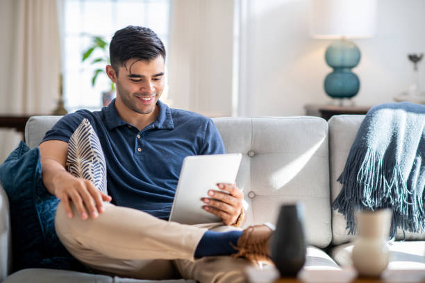 istock Young Hispanic Man Sitting On The Couch With His Tablet 1172268623