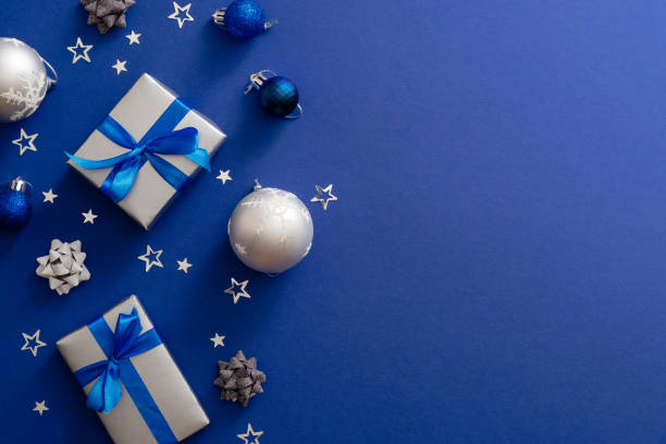 istock Christmas silver gift boxes or presents with bow ribbon, baubles, decorations, confetti on magic dark blue background with copy space. Vintage Xmas greeting card mockup, postcard template. Flat lay 1172269680