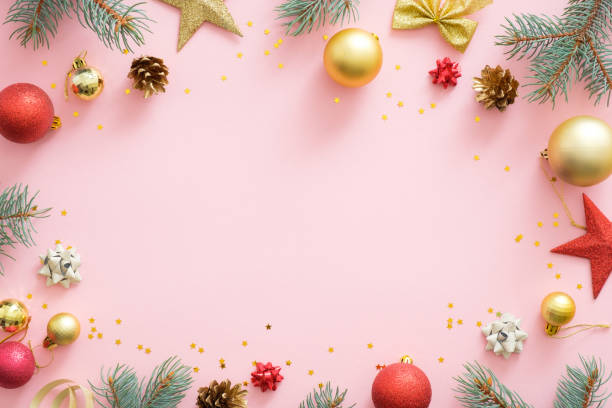 istock Christmas frame made of bright glittering baubles, fir tree branches, pine cones, decorations on pink pastel background. Christmas party invitation card mockup, postcard template. Flat lay. 1172269741