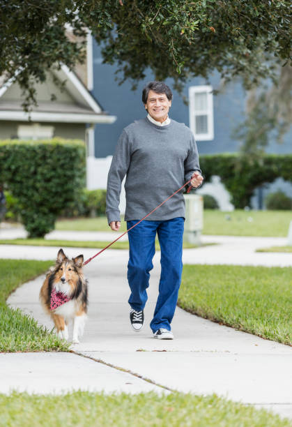 Senior Hispanic man walking dog on leash