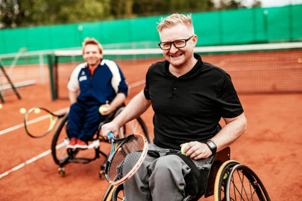 Two determined mature men playing doubles in wheelchair tennis Men in wheelchair playing tennis and conquer adversity wheelchair tennis stock pictures, royalty-free photos & images