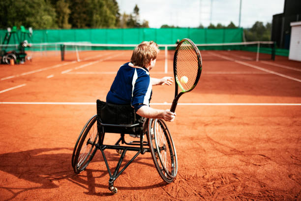 Adult man in wheelchair playing tennis Men in wheelchair playing tennis and conquer adversity wheelchair tennis stock pictures, royalty-free photos & images