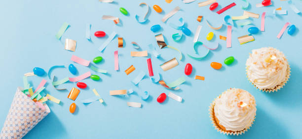 istock birthday hat with confetti and cupcake on blue paper background 1172278169