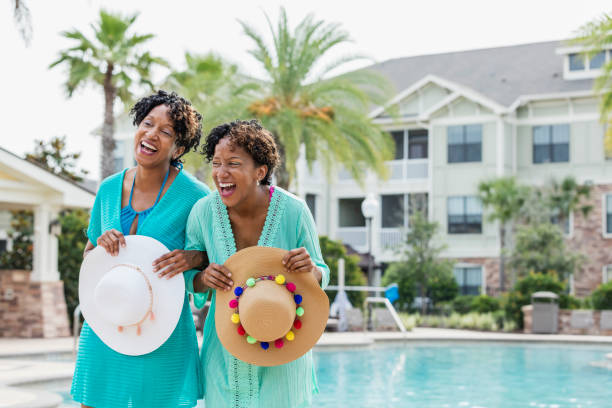 istock Identical twins standing by pool, holding sun hats 1172280229