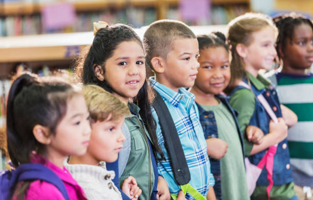 istock Hispanic girl in school standing with classmates 1172283279